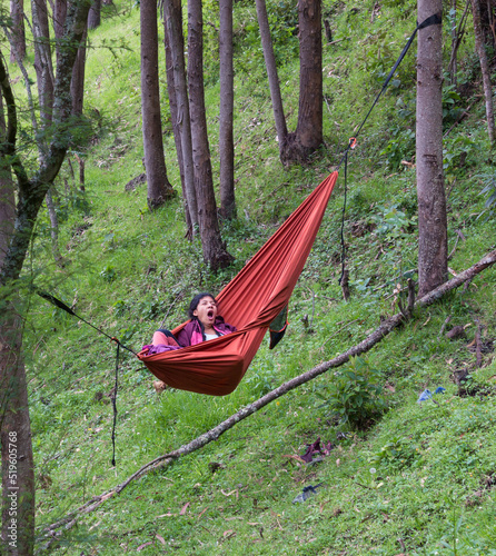 Vertical shot of woman yawning in a hammock in the woods 