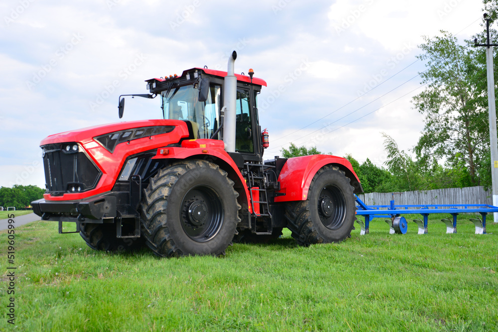 red tractor on green agricultural field with cloudy sky on background