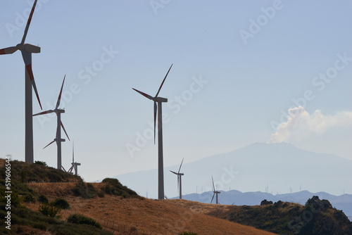 wind turbines on the slopes of the mountains of central Sicily with the Etna volcano at the bottom in the morning lights