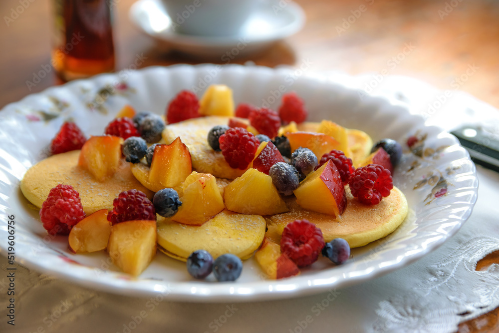 Idea for a tasty and healthy breakfast - pancakes with different fruits with maple syrup and sprinkled with powdered Idea for a tasty and healthy breakfast - pancakes with different fruits with maple syrup and sprinkled with powdered