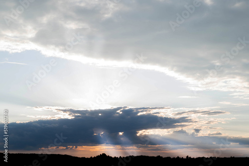 Blurred image of a sunset on a cloudy sky, the rays of the sun break through the clouds.