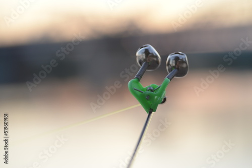 bell alarm is on fishing rod spinning in nature bells of allure are attached to the end of the fishing spinning abandoned in water standing with stretched fishing line Bottom rod and fishing accessori