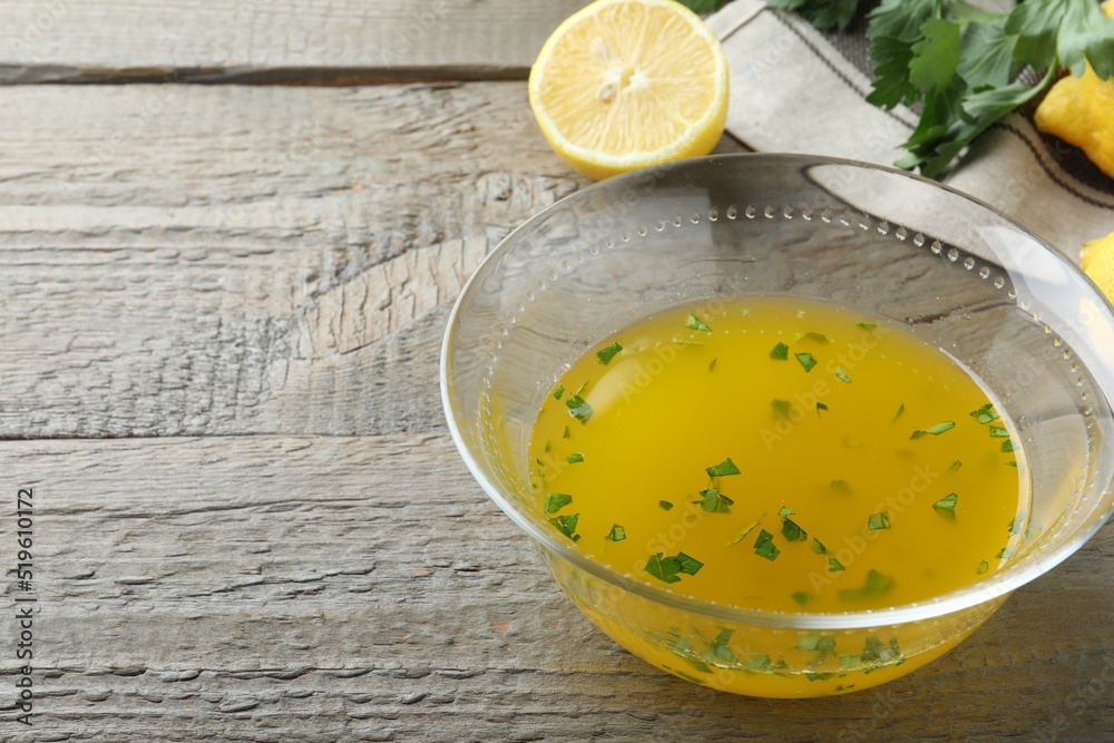 Bowl with lemon sauce and ingredients on wooden table, space for text. Delicious salad dressing Bowl with lemon sauce and ingredients on wooden table, space for text. Delicious salad dressing