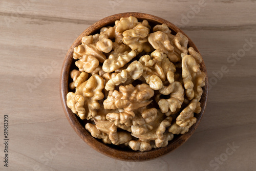 Bowl full of peeled walnuts on a wooden background