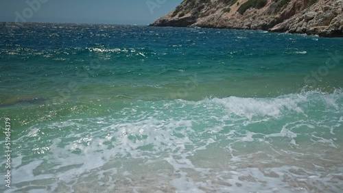 slow motion footage tropical island and sea waves crashing and foaming against pebble rocky beach. rocks coast meeting deep blue ocean water. Tourism in Turkey concept photo