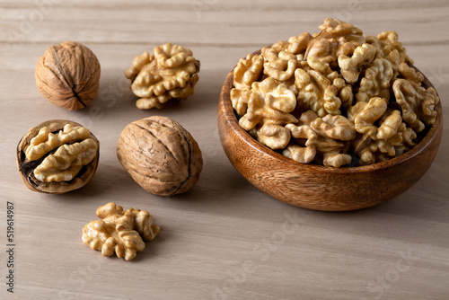 Peeled walnuts and whole walnuts on wooden background