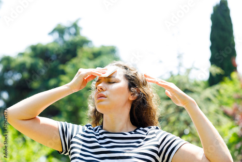 Young woman having hot flash and sweating in a warm summer day.