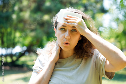 Young woman having hot flash and sweating in a warm summer day.
