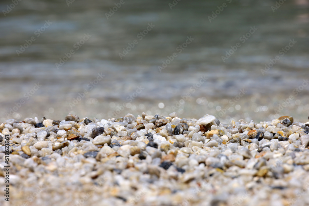 Small pebble stones on sea beach with transparent water. Background for summer vacation Small pebble stones on sea beach with transparent water. Background for summer vacation