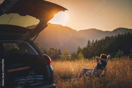 Young beautiful woman traveler enjoying the sunset in the mountains while traveling by car photo