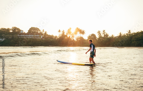 Photography Young teenager boy with colorful surfboard go into sea for surfing