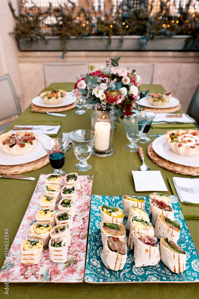 Set of delicious tortilla rolls and pasta bowls on table Set of delicious tortilla rolls and pasta bowls on table