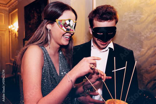 Couple in masquerade masks eating melon during party photo