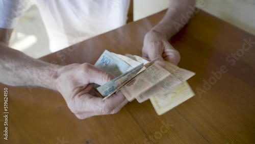Elderly Man Counting Money. Close-up of Brazilian Real Currency.