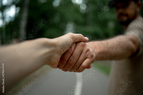 A guy holds a girl by the hand  a young couple walks in the park holding hands  a man pulls a woman behind him 