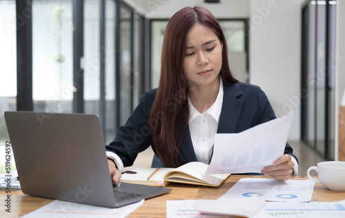 Confused asian businesswoman having a problem on her work or internet problem on laptop computer. Mistake, problem, or unsure with the project. © wichayada