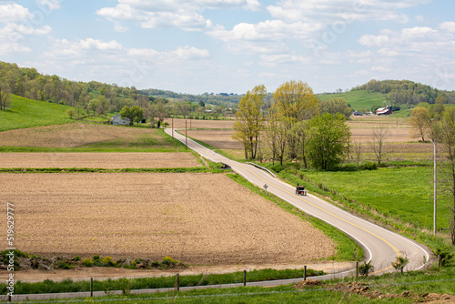 Amish horse and buggy on a winding country road through the farmland of Holmes County, Ohio