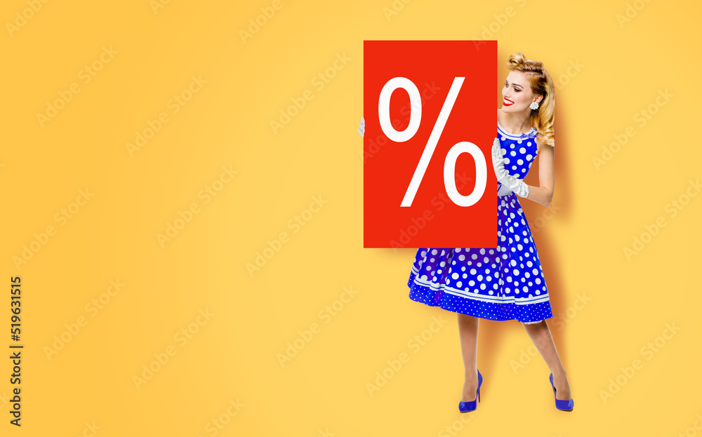 Beautiful woman in pinup dress holding, showing red board with procents % sign. Full body pin up girl with advertising offer, isolated on yellow color background. Sales, discounts rebates ad concept. Beautiful woman in pinup dress holding, showing red board with procents % sign. Full body pin up girl with advertising offer, isolated on yellow color background. Sales, discounts rebates ad concept.