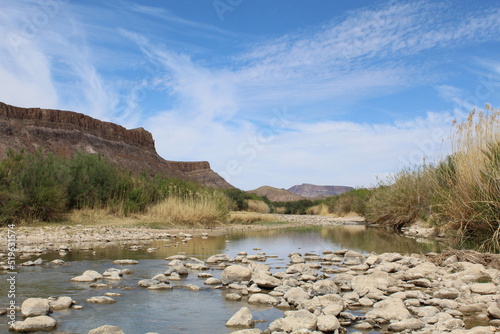 Cirrus clouds and cliffs in the background with the Rio Grande River and rocks at Big Bend Ranch State Park in Texas