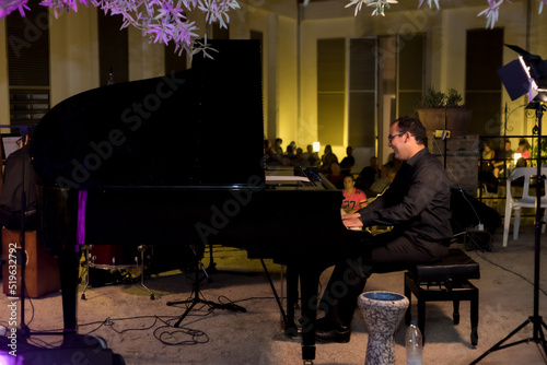 happy pianist playing at an open-air concert with the audience in the background
