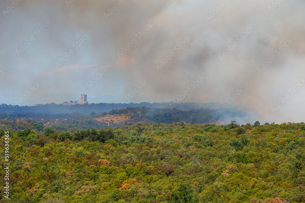 Karst, Miren-Kostanjevica, Slovenia - July 17, 2022: A large forest fire in the Karst (Kras), Slovenia. The fire surrounds the monument on Cerje hill. A military helicopters fighting a fire.