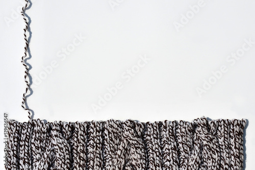 Dissolve hand knitted knitwear made of thick yarn with a braid pattern. edge of knitting with open loops and wavy thread on light background. untangling related things