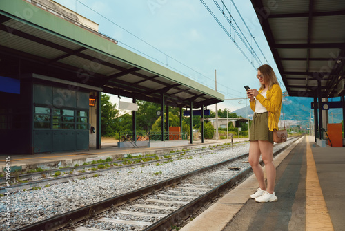 Woman with smartphone is waiting for her train.