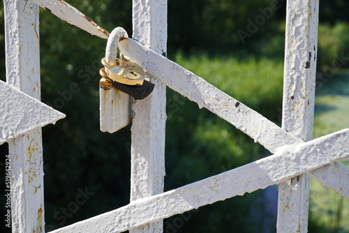 Wedding lock on a white painted fence. Vintage padlock is located on the metal fence.