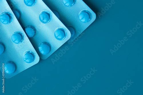 Three blisters with piils. Blue pills on blue background.