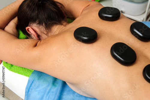 Close-up view of male masseur massaging back and shoulder blades of female lying on massage table at spa salon. Beautiful young woman with perfect skin getting relaxing massage.