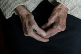  Hands of an old woman on a black background. Aging process.