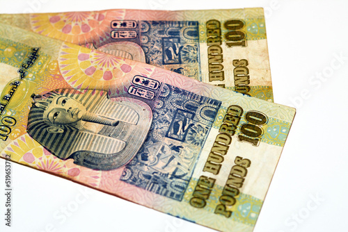Reverse sides of an old 100 LE EGP one hundred Egyptian cash money banknote Tutankhamen's mask above frieze at centre of vertical format, selective focus of withdrawn Egyptian Pounds isolated on white photo