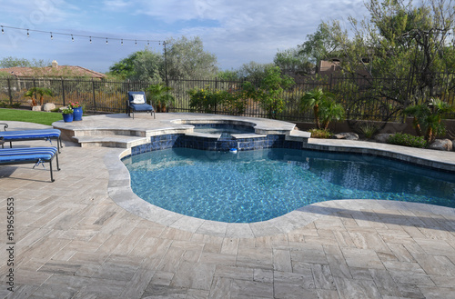 A desert landscaped backyard in Arizona featuring a travertine tiled pool deck.