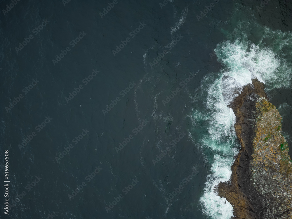 Shooting from a drone. Dark turquoise ocean surface. Foamy waves crash against the rocky shore. Minimalism. There are no people in the photo. Advertising tourist routes, ecology. Shooting from a drone. Dark turquoise ocean surface. Foamy waves crash against the rocky shore. Minimalism. There are no people in the photo. Advertising tourist routes, ecology.