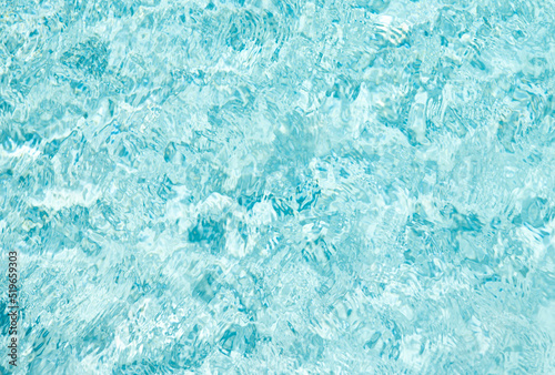 turquoise color backdrop of swimming pool water with ripples in summer