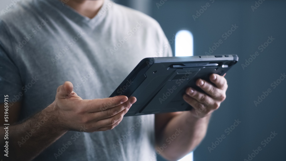 Crop male mechanic in a car service watching a car diagnostics data on a tablet and talking to client about breakdown Crop male mechanic in a car service watching a car diagnostics data on a tablet and talking to client about breakdown