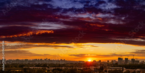 Amazing panoramic view of the big city evening silhouette against the backdrop of incredibly, awesome bright, multi colored clouds at sunset. Kyiv in last days in july 2022. Ukraine. #519659744