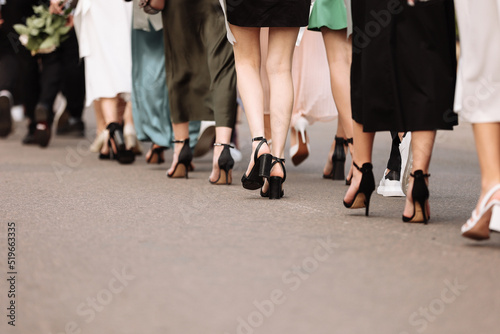 the feet of the group of people are walking outdoors. graduation day. stylish young guys and girls in stylish shoes. slow motion