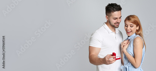 Fotografie Man with engagement ring making marriage proposal to girlfriend on light grey background, space for text