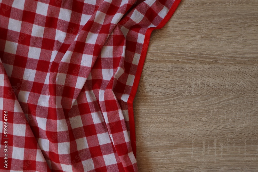 Obraz premium Checkered picnic cloth on wooden table, top view. Space for text