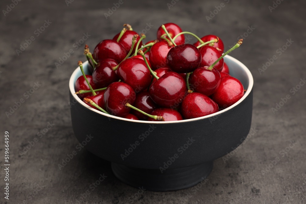 Bowl with ripe sweet cherries on dark grey table Bowl with ripe sweet cherries on dark grey table