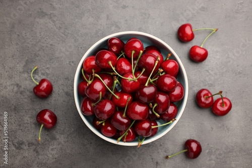 Bowl with ripe sweet cherries on grey table, flat lay