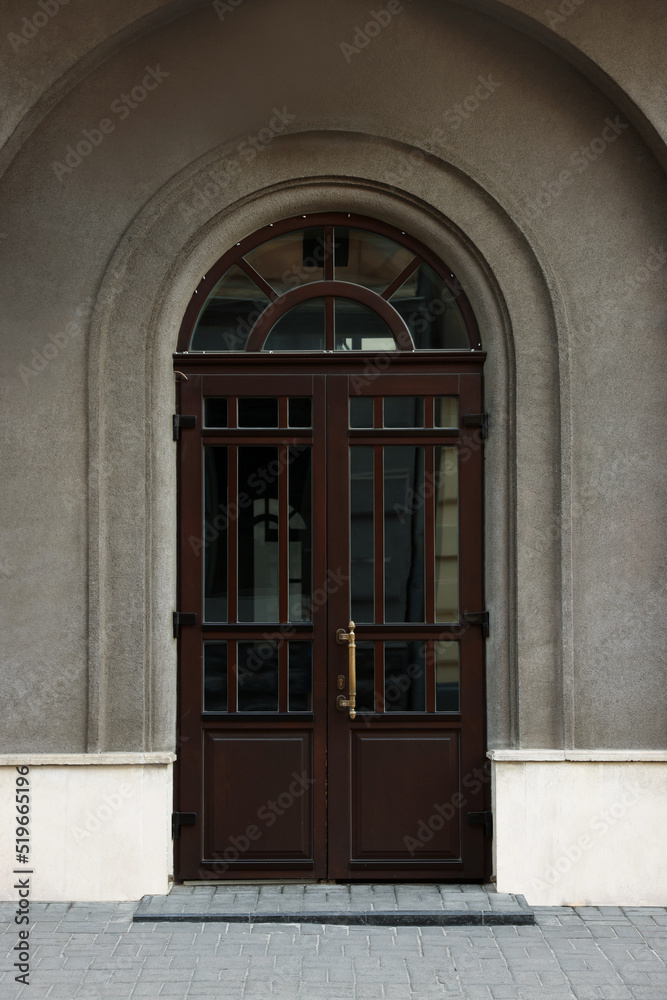 Obraz premium Entrance of house with beautiful arched wooden door and transom window