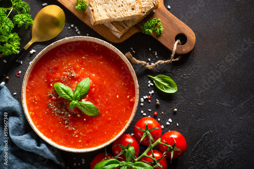 Tomato soup with ingredients on dark stone table. Traditional vegetable soup. Top view with copy space.