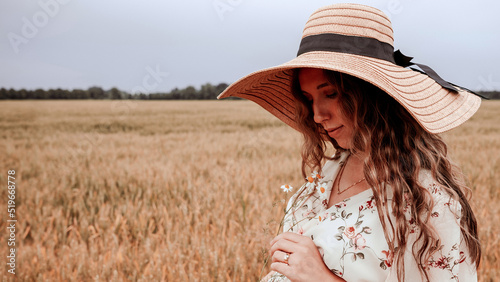 Beauty romantic girl outdoors. Happy young woman in sun hat in summer wheat field at sunset. Copy space, sunset, flare light, summer season. Boho chic style.