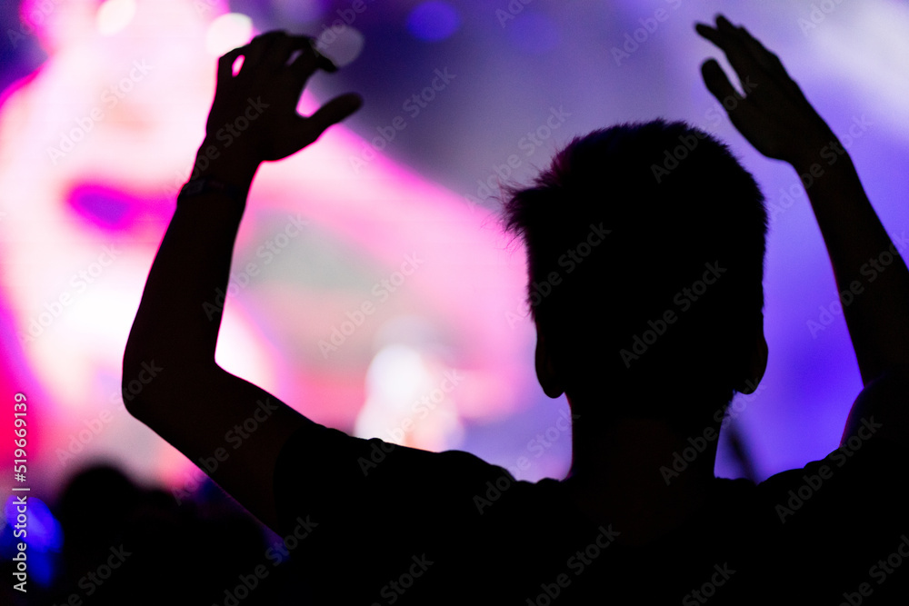 Man with hands up dancing and having fun during concert show on summer music festival. Youth and celebration concept.