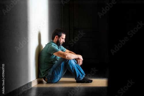 Depressed man sitting in dark hallway