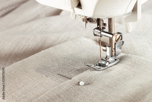 Modern sewing machine presser foot with linen fabric and thread, closeup, copy space. Sewing process clothes, curtains, upholstery. Business, hobby, handmade, zero waste, recycling, repair concept photo