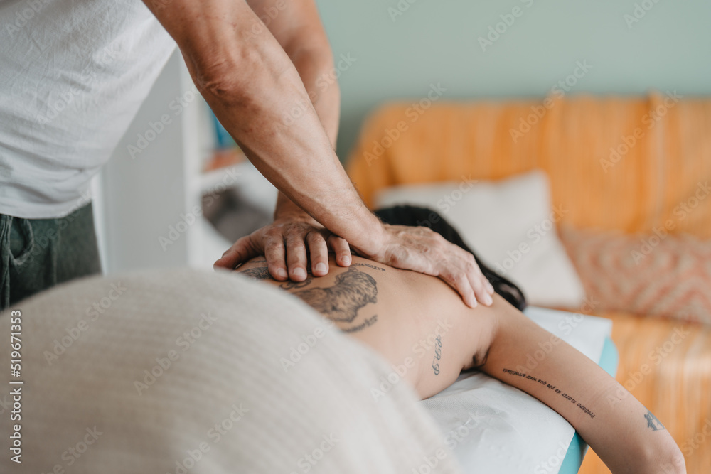 therapist places his hands on the patient's back while she is lying down. therapist places his hands on the patient's back while she is lying down.