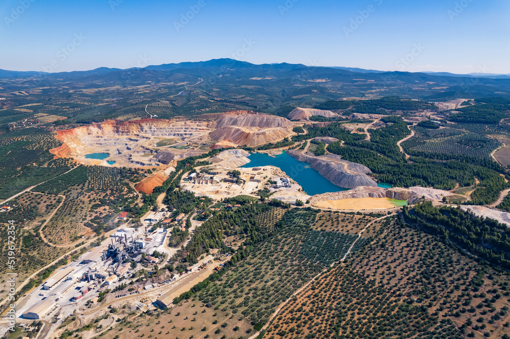 Open-mining in Greece. Aerial drone shot of a open-mine surrounded by trees and hills. Clear blue sky. High quality photo